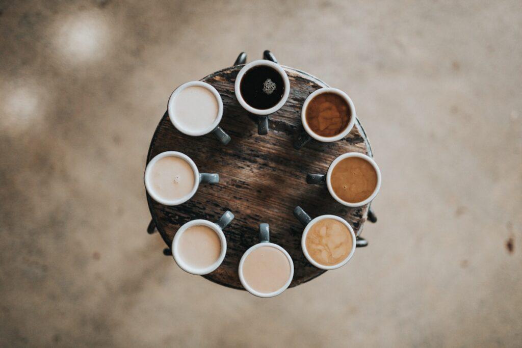 flat lay photography of eight coffee latte in mugs on round table